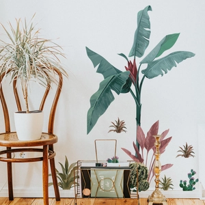 Detail of tropical monstera and palm leaf wall decals on a modern minimalist white wall