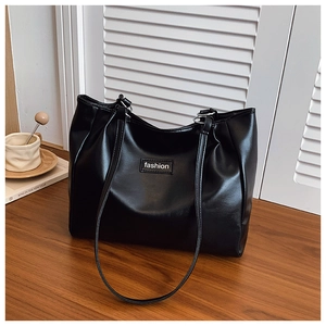 Detail of minimalist black tote bag featuring delicate PU leather texture and fashion logo