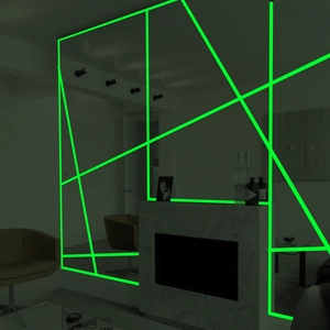 Luminous self-adhesive tape glowing bright green in dark room on interior wall surfaces