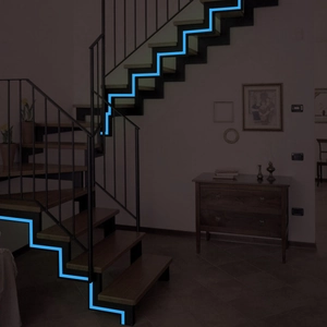 Glow in the dark stair safety tape in luminous cyan blue on wooden staircase steps