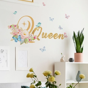 Détail du sticker mural doré Queen avec fleurs et papillons colorés sur un mur blanc pur