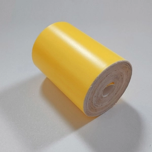 Detailed close-up of yellow self-adhesive luminous tape in a compact spiral roll structure