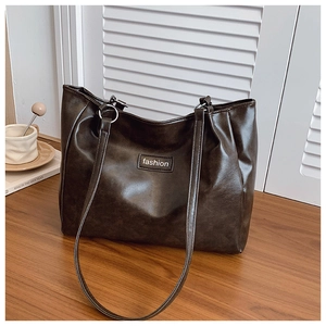 Detail of dark brown tote bag showing matte leather texture and silver metal rings