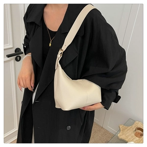 Close-up of cream leather hobo bag with pebble texture and adjustable gold buckle strap