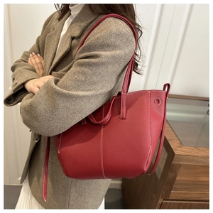 Detail of dark red lychee leather tote bag with white stitching shown on shoulder