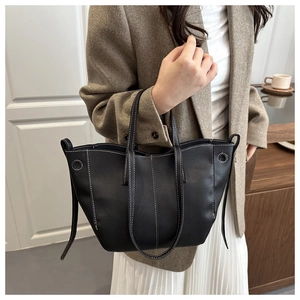 Close-up of black litchi pattern leather tote bag featuring contrast white stitching details