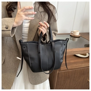 Close-up of black lychee grain leather tote bag with white stitching detail and dual handles
