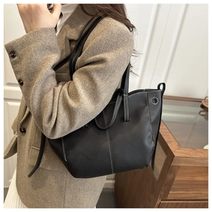 Detail of black tote bag with white contrast stitching and pebbled leather texture