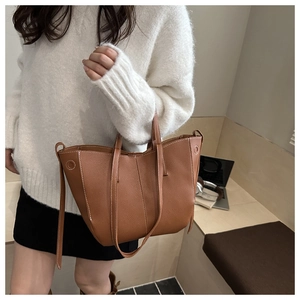 Close-up of brown litchi pattern leather tote bag with stylish white contrast stitching