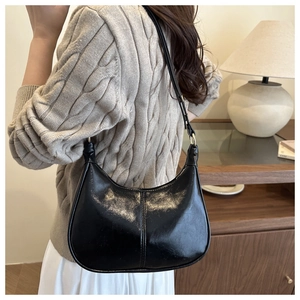 Detail shot of black patent leather hobo bag showing the glossy texture and stitching