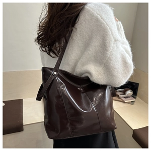 Mannequin portant un grand sac cabas en cuir verni marron foncé au design minimaliste chic