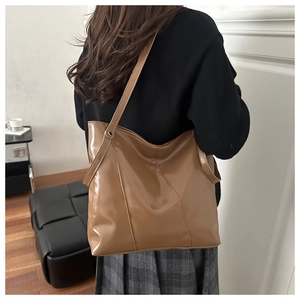 Détail d'un sac cabas caramel brillant avec coutures en V porté par un mannequin