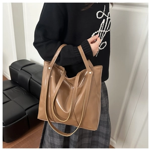 Détail du sac cabas en cuir marron brillant avec clous métalliques et bretelles d'épaule