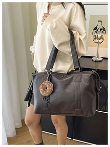 Detail of dark brown PU leather tote bag with soft texture and plush donut accessory