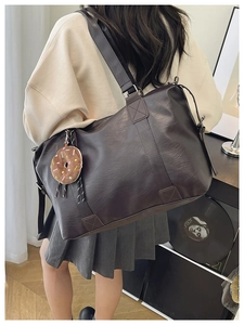 Detail of dark brown faux leather tote with reinforced handles and plush charm