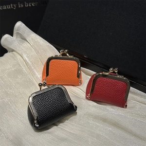 Three mini leather coin purses in black, orange, and red with gold metal clasps