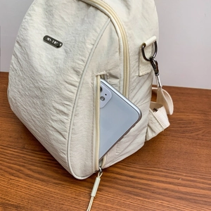 Dettaglio della tasca laterale dello zaino in nylon beige con uno smartphone