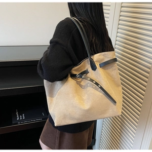 Detail of minimalist beige suede tote bag with black leather straps and eyelet buckle