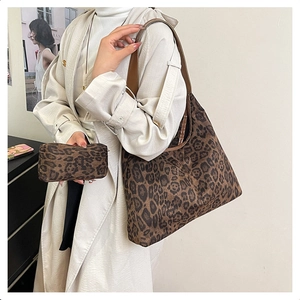 Detail showing a leopard print tote bag with matching zippered pouch and leather strap