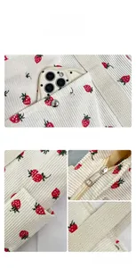 Detail of corduroy strawberry tote featuring metal zipper closure and woven strap