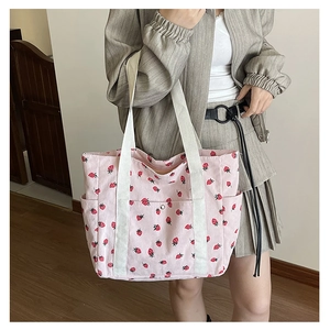 Close-up of pink corduroy strawberry tote bag with side pocket shown on model