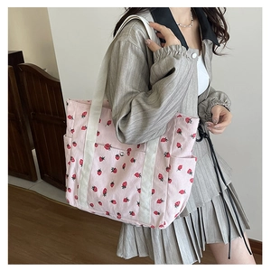 Detail view of pink corduroy tote bag with strawberry print and multiple pockets