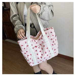 Detail of pink corduroy tote bag with strawberry print and white canvas handles