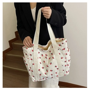 Detail view of corduroy tote bag with strawberry print and side pockets for storage