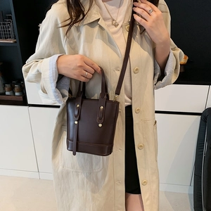 Deep brown minimalist bucket handbag with gold rivets and adjustable shoulder strap