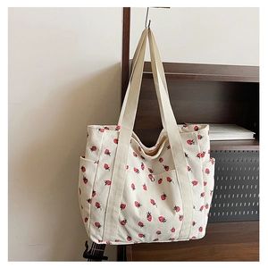 Detailed close-up of corduroy tote bag with strawberry print and side storage pocket