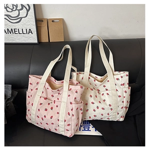 Detail view of pink and off-white corduroy tote bags with cute strawberry print and side pockets