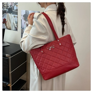 Close-up of red quilted tote bag with silver bow buckle and soft faux leather texture