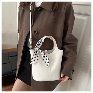 Detail of white lychee leather bucket bag with polka dot scarf and adjustable strap