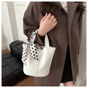Détail d'un sac seau en cuir litchi blanc orné d'un foulard en soie à pois noir et blanc