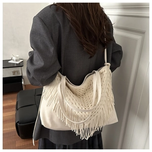 Detail of bohemian woven tote bag featuring intricate lace crochet and long tassels
