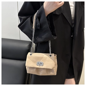 Detail of beige suede crossbody bag with silver chain strap and crystal lock buckle
