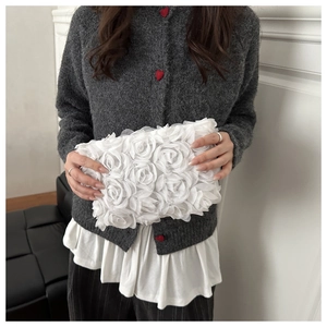 Detail of elegant white mesh clutch bag with 3D floral petals held by a model
