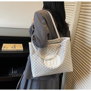 Détail du sac cabas blanc cassé avec imprimé lettre M gris et écusson logo rond
