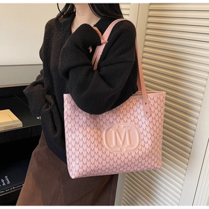 Sac fourre-tout rose avec imprimé monogramme lettre M porté à l'épaule sur un pull noir