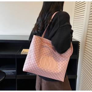 Détail d'un sac cabas rose avec gaufrage à motif M et logo en situation réelle