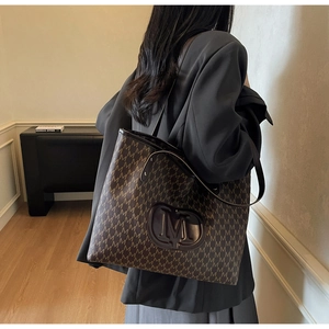 Gros plan du sac cabas en cuir marron café avec motifs monogrammes et logo M