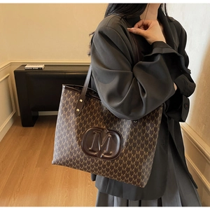 Détail d'un sac cabas marron vintage avec motif M et logo embossé élégant