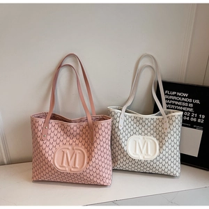 Détail de sacs cabas rose et beige avec logo M embossé et imprimés de lettres stylés