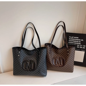 Détail de cabas noirs et marron avec imprimé monogramme et logo M ovale