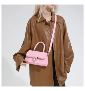Détail du sac matelassé rose avec fermoir doré porté sur un manteau en cuir marron rétro