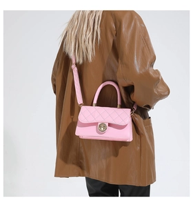 Sac à bandoulière rose matelassé avec fermoir rotatif porté par un mannequin en cuir