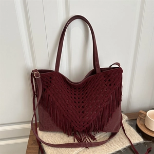 Bohemian burgundy tote bag with fringe tassels and shoulder strap on minimalist background