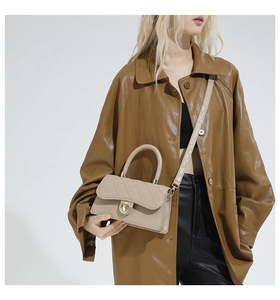 Détail du sac bandoulière beige matelassé avec fermoir rotatif en anneau doré
