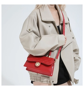 Détail d'un sac bandoulière rouge matelassé avec fermoir doré rotatif et fine bandoulière