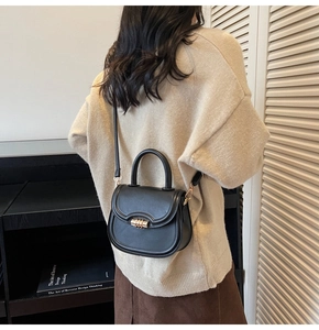 Close-up of black leather saddle bag with golden metal knob buckle and adjustable strap